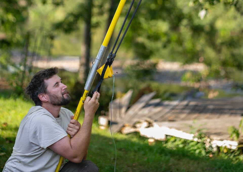 Mitarbeiter bedient Hochentaster im Garten – Baumpflege Enzesberger